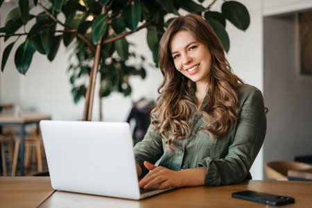 Shes always happy to be in the office. Portrait of a young focussed female designer working on her laptop and digital tablet at the office during the day. High quality photoの写真素材