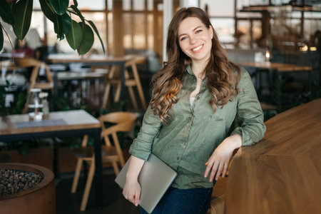 Beautiful young concentrated business woman wearing shirt using laptop while standing in modern workspace. High quality photoの写真素材