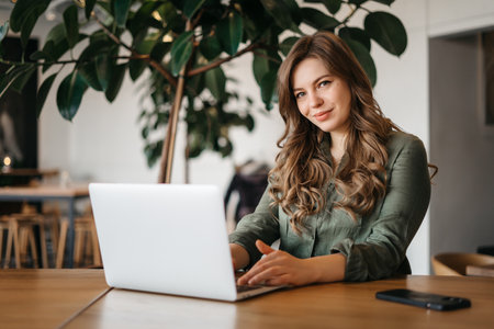 Businesswoman looking and smiling for the camera, using a laptop. High quality photoの写真素材
