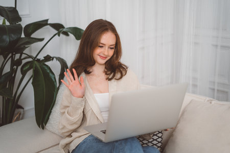 Happy smiling redhead girl using laptop at living room at home, watching funny video, learning language, video calling, mother working onlineの写真素材