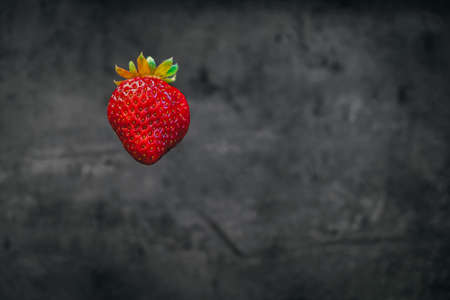 juicy strawberries floating in the air on a dark blurry background. fresh fruits. summer menu
