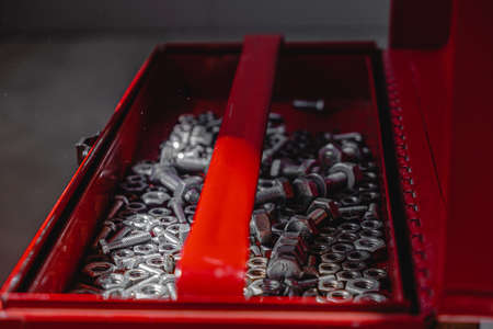 open red tool box on concrete, inside nuts and bolts. lock. light and shadow from the window. close upの写真素材