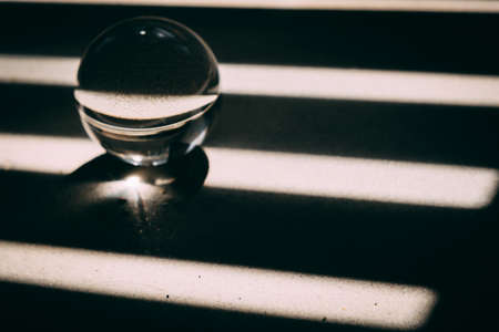 glass transparent ball rolls along dark and light lines, light and shadow. the concept of good luck...