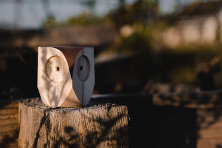 a small wooden toy owl with big eyes sits on a wooden fence. eco toys conceptの写真素材