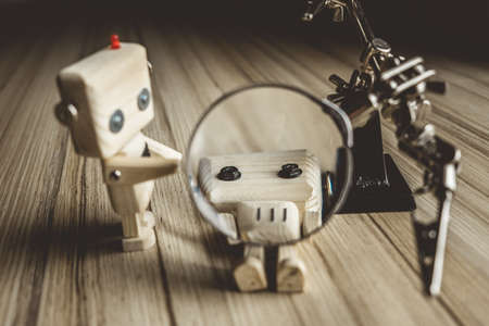 wooden robot android lies on the table under a magnifying glass. metal clamps with a magnifying glass. surgical operation conceptの写真素材