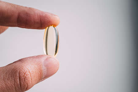 yellow transparent omega 3 capsules in hand. taking medications. nutritional supplements