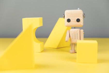 wooden robot toy. environmentally friendly toys for children. on a yellow and gray background, with yellow geometric shapesの写真素材