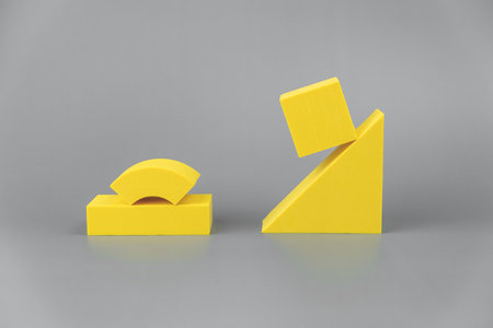 group of volumetric yellow geometric shapes on a gray background. simple shapes. the cube is hovered on one edge of the triangleの写真素材