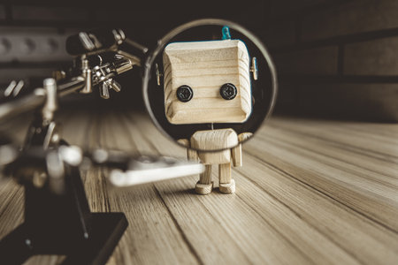 wooden robot android stands on a table under a magnifying glass. metal clamps with a magnifying glass. the face of a robot in the beautifying glass. human study conceptの写真素材