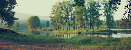 Panorama of calm river with an island with treesの写真素材
