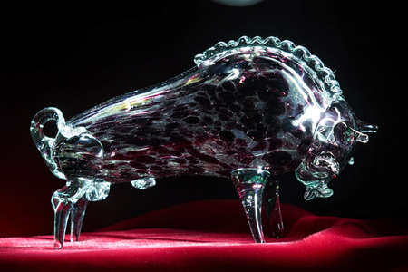 Illuminated glittering crystal glass bull on red velvet close upの写真素材
