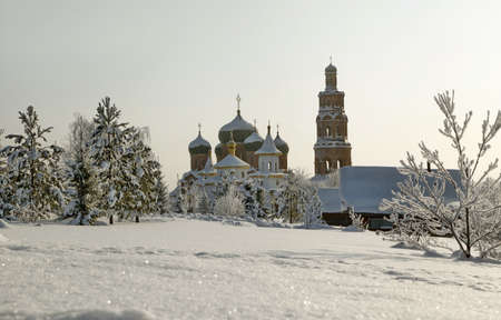 Orthodox monastery with snow covered domes in snowy area with bare treesの写真素材