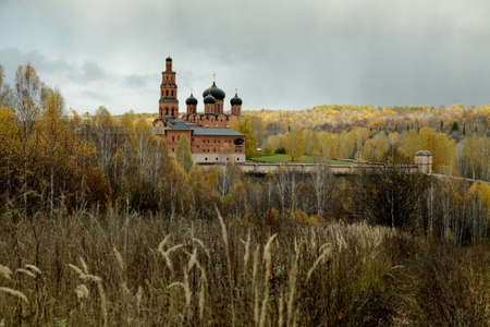 Cloudy sky over Orthodox monastery and the autumn forest