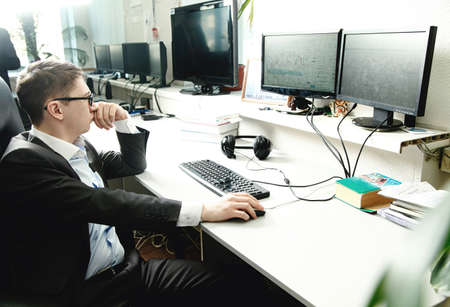 Man working at a computer in the office with monitorsの写真素材