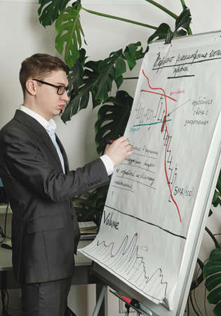 Man draws trading diagramms on the papper presentation boardの写真素材