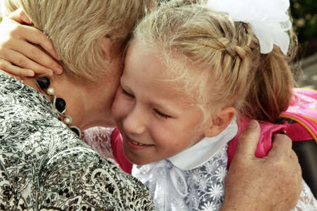 Little girl tenderly embraces grandmother in day back to schoolの写真素材