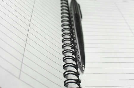 Metallic ball pen on office spiral notebook (manual focus on the pen tip) close up