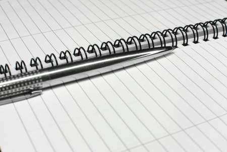 Metallic ball pen on office spiral notebook (manual focus on the pen tip) close upの写真素材