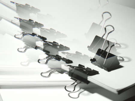Black binder clips clamping the paper close up white background with lense distortion filterの写真素材