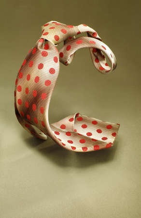 Brown with red spotted necktie on green fabric background, fashion accessory close upの写真素材