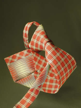 Red with yellow checkered necktie on green fabric background, fashion accessory close upの写真素材