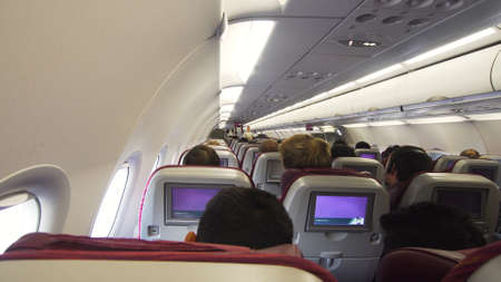 Interior passengers airplane with people on seats. Aircraft cabin with rows of seats. Passengers...