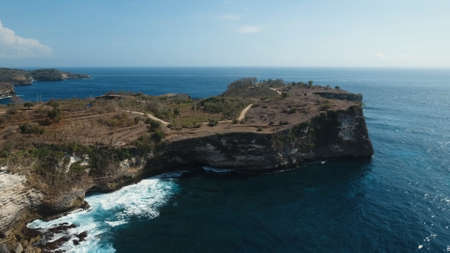 Aerial view of Rocky coast with high cliffs, sea surf with breaking waves on the coast, Nusa Penida, Indonesia. Ocean with waves and rocky cliff. Travel conceptの写真素材