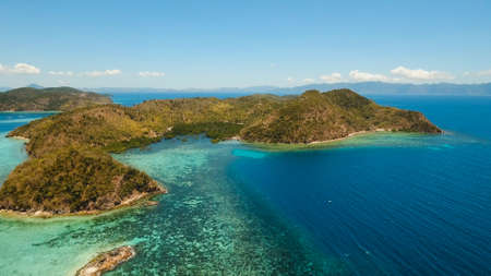 Aerial view: Lagoon with blue, azure water in the middle of small islands and rocks, Palawan. Beach,...