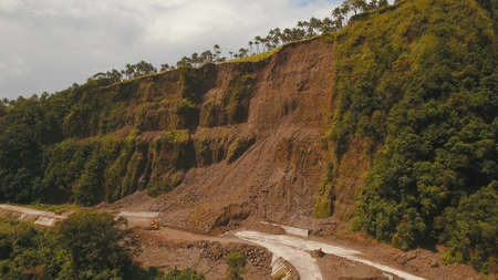 Landslides and rockfalls on the road in the mountains, Camiguin. Aerial view: mud and rocks blocking the road. Destroyed rural road landslide damaged in powerful flood. Collapsed on the mountain. Philippines.の写真素材