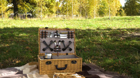 Wooden basket for picnic with plates. Basket for a picnic in the park on a sunny day. Outdoor picnic at sunny day.の写真素材