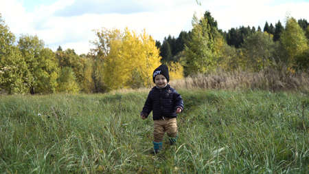 Little boy walks in the park in autumn day. Little boy running on the countryside road.Kid in the park.の写真素材