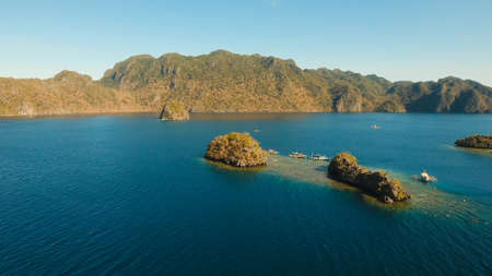 Aerial view: beach, tropical island, sea bay and lagoon, mountains with rainforest, Palawan. Lagoon with blue, azure water in the middle of small islands and rocks. Busuanga. Seascape, tropical landscape. Philippines.の写真素材