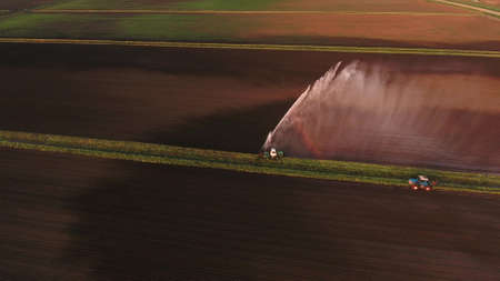 Irrigation equipment watering freshly seeded field.Irrigation at sunset.Irrigation of farmland to ensure the quality of the crop. Aerial view:irrigation system watering a farm field.の写真素材