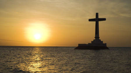 Sunken Cemetery cross in Camiguin Island, Philippines. Large crucafix marking the underwater sunken cemetary of the coast of camiguin island near mindanao in the Philippines. Catholic cross in the water on the background of sky and clouds.. The Sunken Cemetery marks the swept remains of locals when Mt. Vulcan Daan. Travel concept.の写真素材