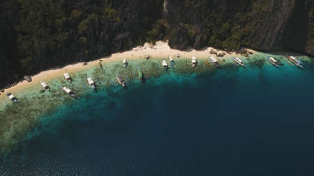Tropical lagoon with turquoise water and white sand. Blue Lagoon with tourists and motor boats. Beautiful beach. Tropical bay in El Nido. Aerial view: bay and the tropical island. Seascape: mountains, ocean. Philippines, El Nido. Travel concept.の写真素材
