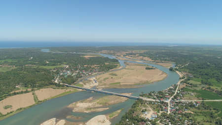 River passing through farmlands and flowing into sea. Philippines, Luzon. Aerial view of river,...