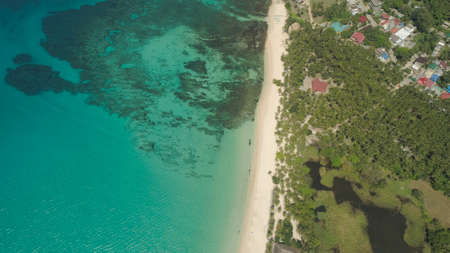 Aerial view of beautiful tropical beach Saud with turquoise water in blue lagoon, Pagudpud, Philippines. Ocean coastline with sandy beach and palm trees. Tropical landscape in Asia.の写真素材