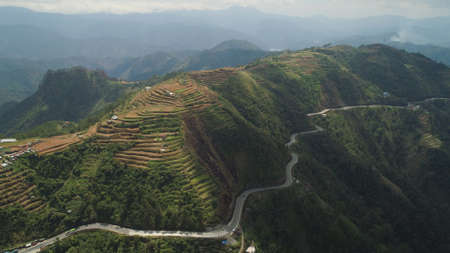 Aerial view of rice terraces and agricultural farm land on the slopes of mountains valley. Cultivation of agricultural products in mountain province. Mountains covered forest, trees. Cordillera region. Luzon, Philippines, Baguio province.の写真素材