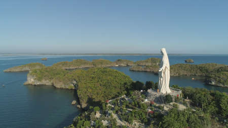 Statue of Jesus Christ on Pilgrimage island in Hundred Islands National Park, Pangasinan, Philippines. Aerial view of group of small islands with beaches and lagoons, famous tourist attraction, Alaminos.の写真素材