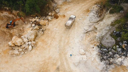 Excavator loads the truck in a limestone quarry. Aerial view wheel loader excavator machine loading...