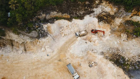 Excavator loads the truck in a limestone quarry. Aerial view wheel loader excavator machine loading...
