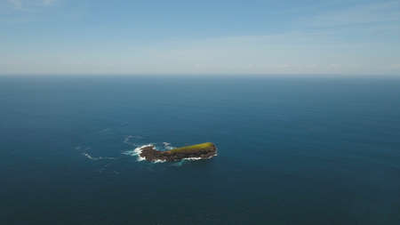 Tropical rocky island in the sea. Aerial view tropical island among the ocean. Waves break on the...