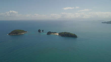 Aerial view island with sand beach and turquoise water in blue lagoon among coral reefs, Caramoan Islands, Philippines. Landscape with sea, tropical beach.の写真素材