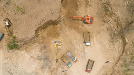 excavator at construction site cuts hill and loads truck with earth. aerial view Heavy machinery prepares the countryside for construction. Excavators are been used in large and small scale constructions Indonesiaの写真素材