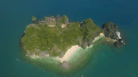 Aerial view Matukad island with sand beach and turquoise water in lagoon among coral reefs, Caramoan...