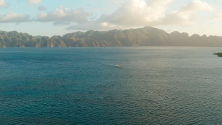 Aerial view seascape bay with islands and mountains sunset. tour boat in sea. traditional Filipino wooden outrigger boat called a banca . Motorboat crossing ocean. Banca boat in the Philippines Palawanの写真素材
