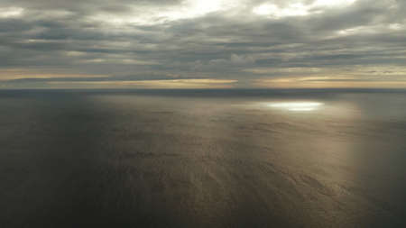 Dramatic sky with clouds over the sea during sunset in cloudy weather, aerial view. Sunset over...