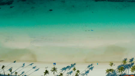 White sandy beach with tourists and azure water of the lagoon,copy space for text, top view. Ocean with waves and tropical beach. Summer and travel vacation conceptの写真素材