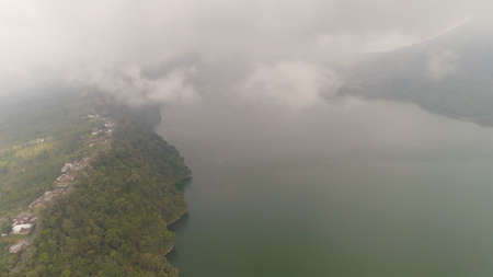 lake Buyan shores covered with tropical vegetation on cloudy day. mountain with slopes covered...