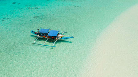 Boat on a tropical beach in the turquoise water of the lagoon from above. Summer and travel vacation concept. Mansalangan sandbar. Beach at the atoll. Balabac, Palawan, Philippines.の写真素材